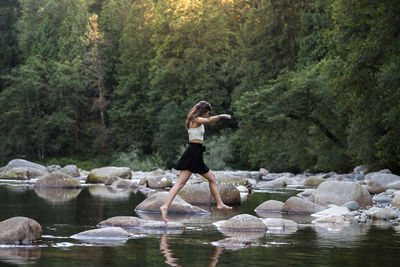 Full length of young woman in lake at forest