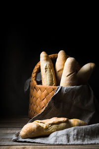 Close-up of bread in basket on table against black background