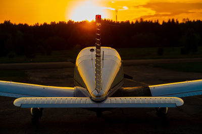 Airplane by lake against sky during sunset