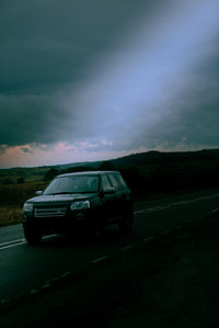 Car on road against sky at dusk