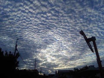 Low angle view of silhouette cranes against sky