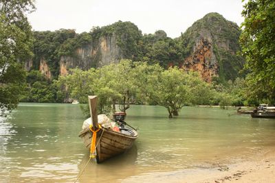 Boat sailing on river by trees against sky