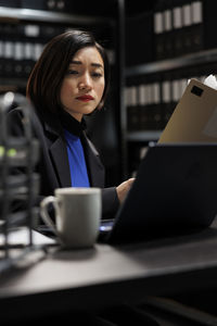 Portrait of young woman using laptop at table