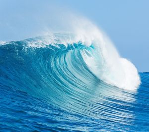 Aerial view of sea waves splashing against clear blue sky