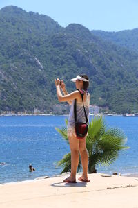 Full length of woman standing on beach against clear sky