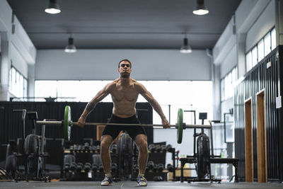 Male athlete lifting barbell in gym