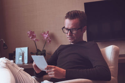 Man looking at papers while sitting on seat at home