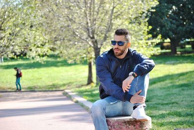 Man wearing sunglasses sitting in park