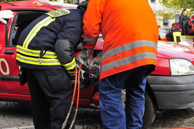 Rear view of firefighters by car