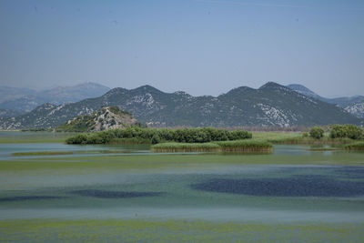 Scenic view of lake and mountains against clear sky
