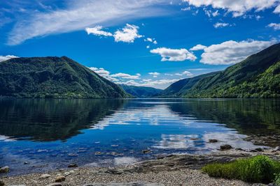 Scenic view of lake and mountains against blue sky