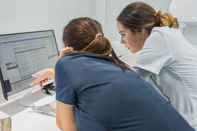 Side view of medical practitioners browsing data on modern computer while working in lab of modern hospital together