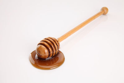 Close-up of honey dipper over white background