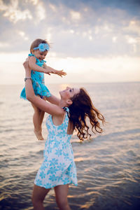 Mother holding her child at sunset by the sea