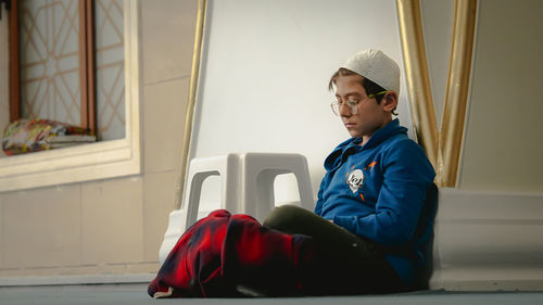 Side view of young man sitting on window