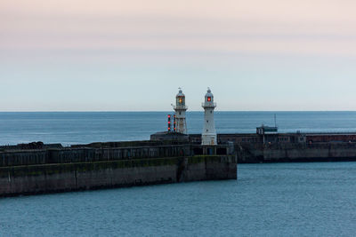 Lighthouse by sea against sky