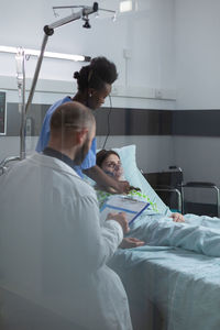 Rear view of man sitting on bed at clinic