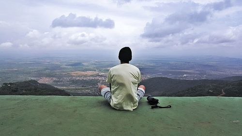 Rear view of man by camera sitting at observation point