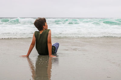 Rear view of boy sitting at beach