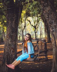 Full length portrait of woman sitting on swing in park