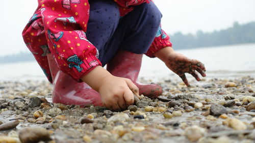 Midsection of girl playing on pebble beach 