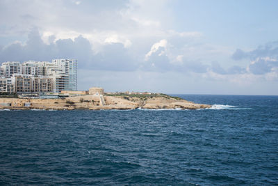 Buildings by sea against sky