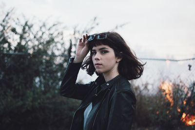 Portrait of young woman standing against fence