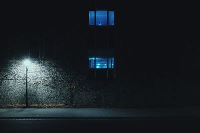 Illuminated street light against building at night