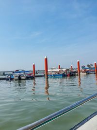 Boats moored in sea against blue sky