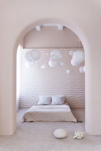 Minimalist bedroom with wavy wall design, natural light from the side window. round arch in the wall