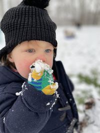 Cute boy eating food outdoors during winter