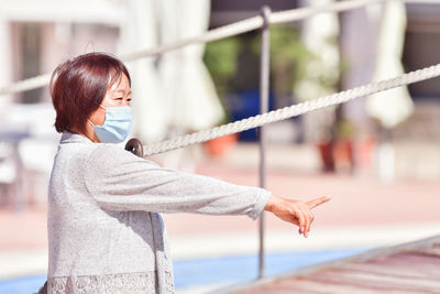 Woman holding umbrella standing by railing