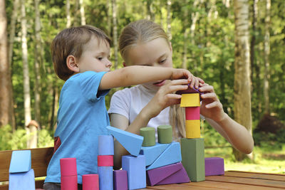 Cute siblings playing with toy blocks outdoors