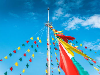 Low angle view of multi colored flags hanging against blue sky