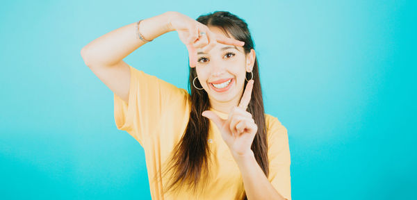 Portrait of young woman with arms crossed against blue background