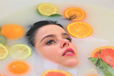 Close-up of woman taking bath with fruits in bathtub