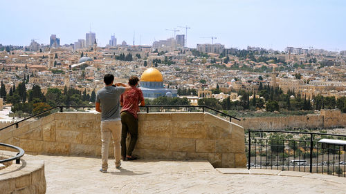 Rear view of people looking at cityscape during sunny day