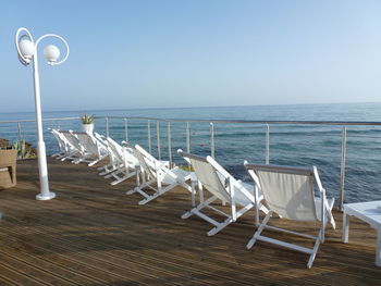 Deck chairs on beach against clear sky