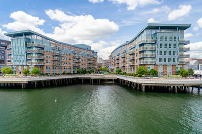 Bridge over river by buildings against sky in city