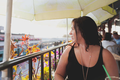 Young woman looking away while sitting at restaurant