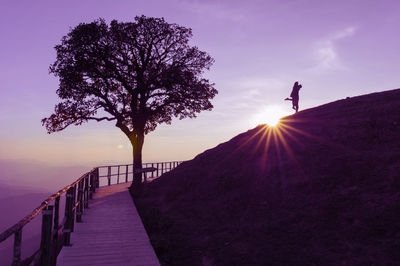 Silhouette couple on hill against sky during sunset