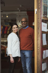 Portrait of smiling owners standing at store entrance