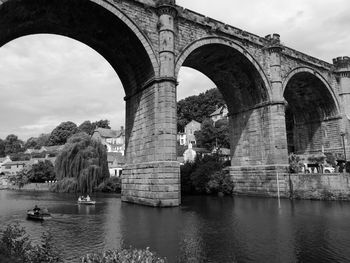 Arch bridge over river against sky