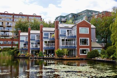 Buildings by lake against sky
