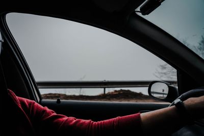 Midsection of person seen through car windshield