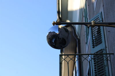 Low angle view of lamp against building against clear blue sky