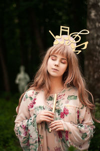 Young woman with arms raised standing outdoors