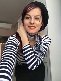 Portrait of smiling woman wearing scarf and flat cap at home