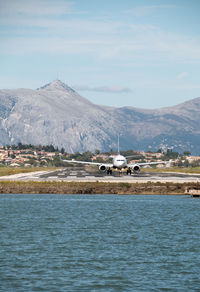 Scenic view of sea by mountains against sky