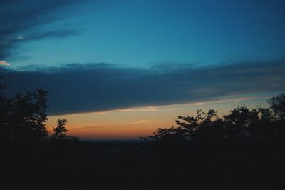 Silhouette trees against dramatic sky during sunset